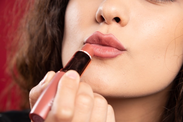 Curly woman applying lipstick.