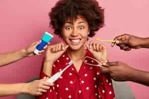 Free photo curly woman cares about teeth, holds dental floss, surrounded by toothpaste and brushes