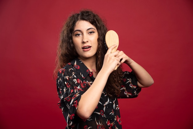 Curly woman combing her hair.