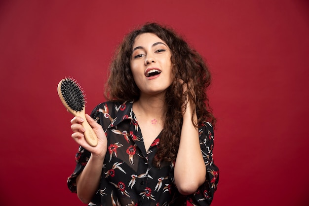 Curly woman holding comb.