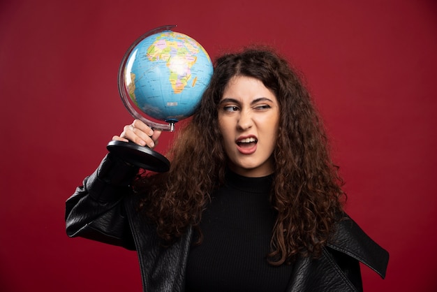 Free photo curly woman holding globe.