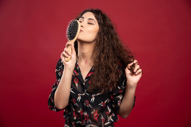 Curly woman kissing comb.