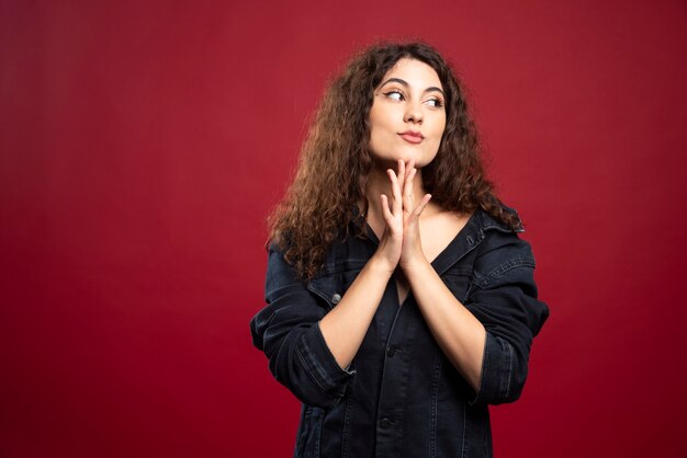 Curly woman looking at her side with her hands closed.