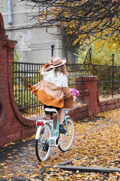 Curly woman riding on street with woman's retro bike