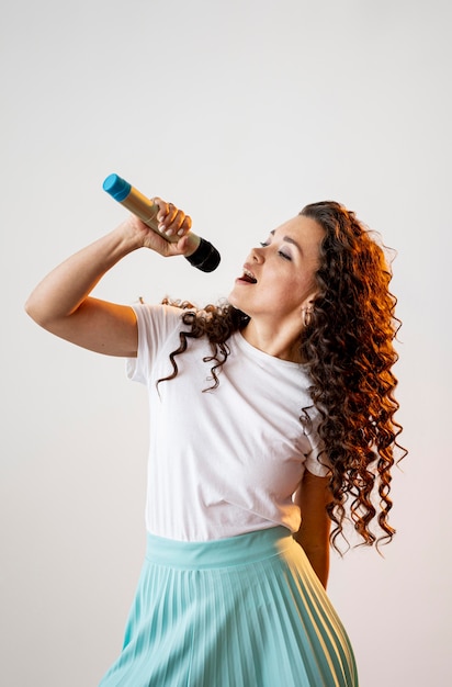 Curly woman singing at a microphone indoors