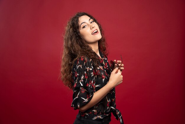 Curly woman with sunglasses standing.