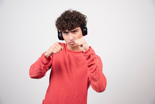 Curly young man listening to song and punching.