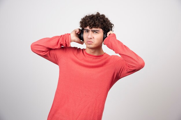 Curly young man with headphones listening to song.