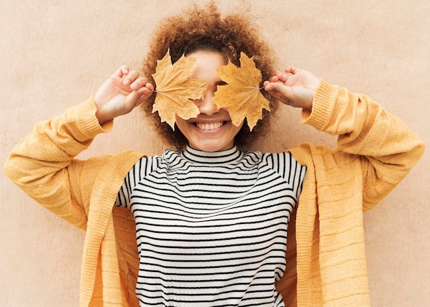Free photo curly young woman covering her eyes with leaves