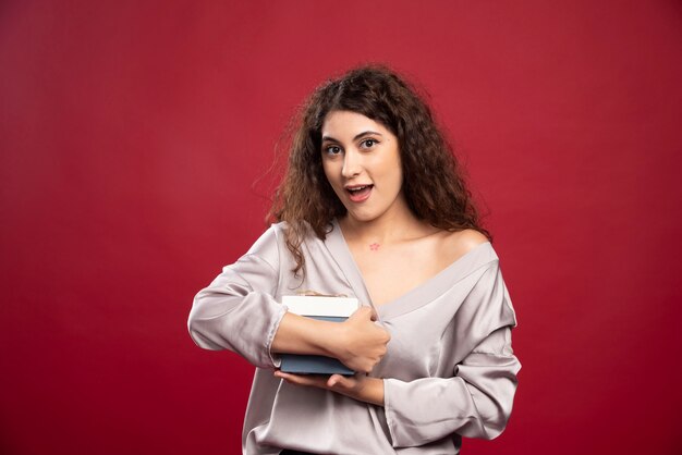 Curly young woman holding blue gift box.