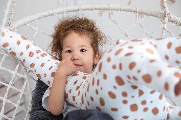 Curlyhaired child plays with a giraffe toy on a swing