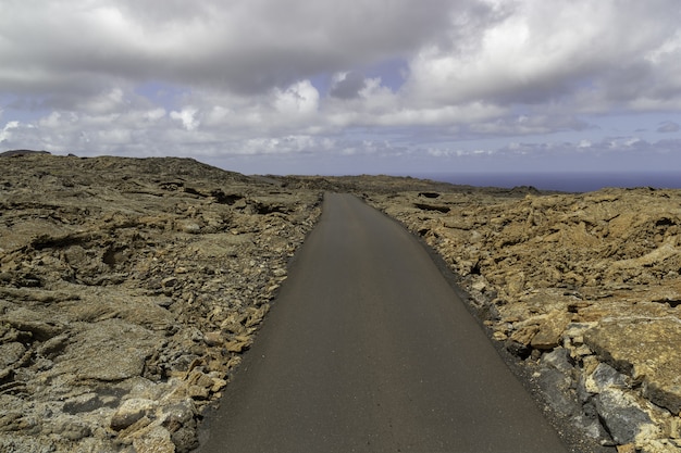 스페인 Timanfaya 국립 공원의 흐린 하늘 아래 바위로 둘러싸인 매력적인 도로