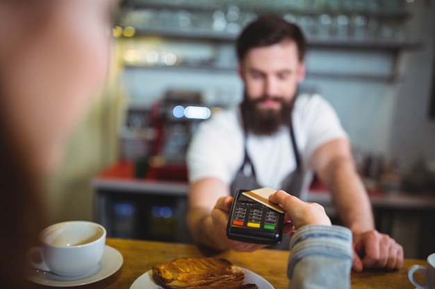 Customer making payment through payment terminal at counter