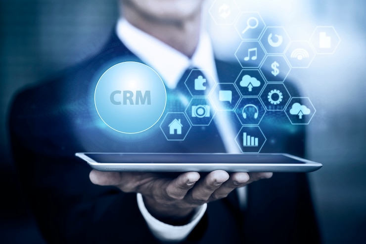 A man holding a tablet with a CRM icon representing CRM dynamics.