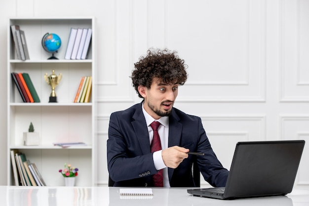 Customer service curly brunette young man in office suit with laptop excited