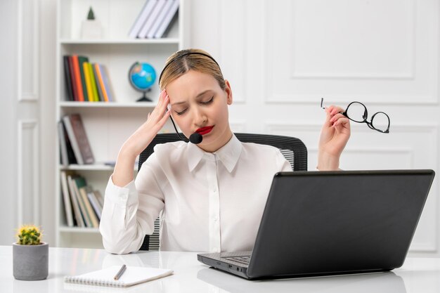 Customer service cute beautiful girl with computer and headset tired taking glasses off