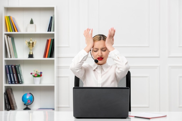 Customer service cute blonde girl in office shirt with headset computer annoyed holding temples