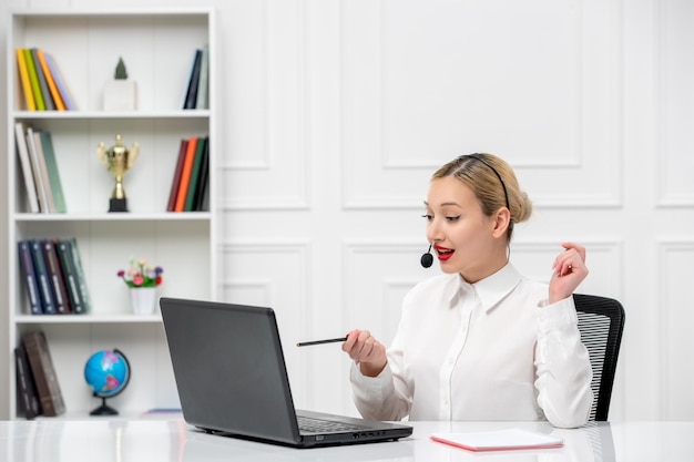 Customer service cute blonde girl office shirt with headset and computer pointing with pen