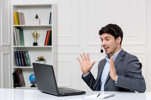 customer service cute guy in grey suit with computer and headset excited waving hands