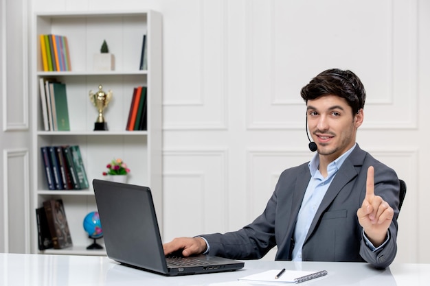 Обслуживание клиентов милый парень в сером костюме с компьютером и гарнитурой, показывающий стоп-жест
