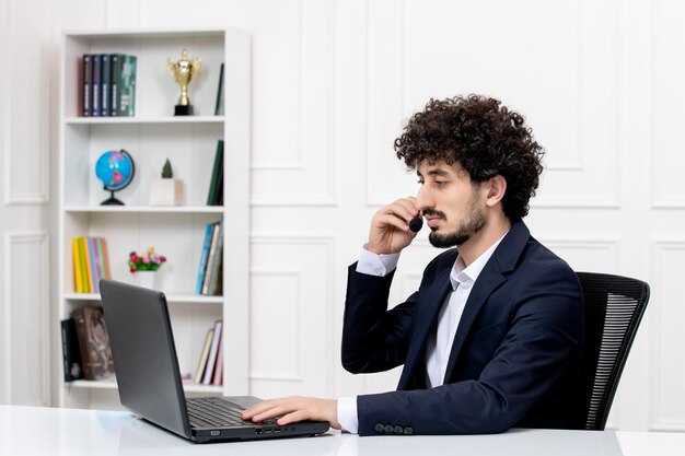 Customer service handsome curly man in office suit with computer and headset on the call