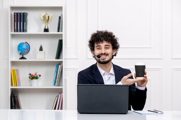 Customer service handsome curly man in office suit with computer and headset happy for a coffee