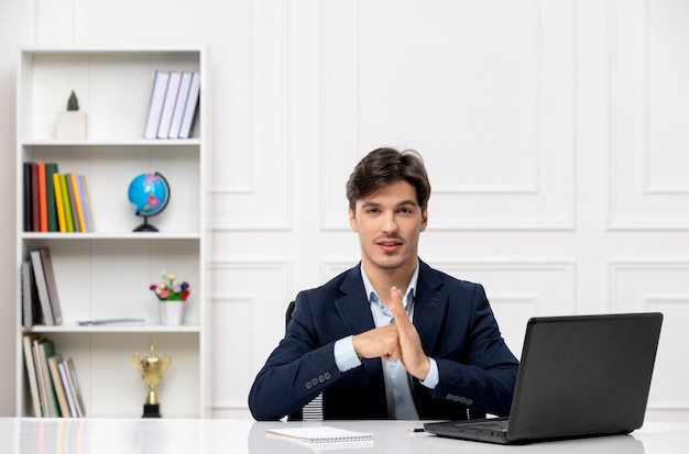 Customer service handsome guy in the office suit with the computer confidently holding fist