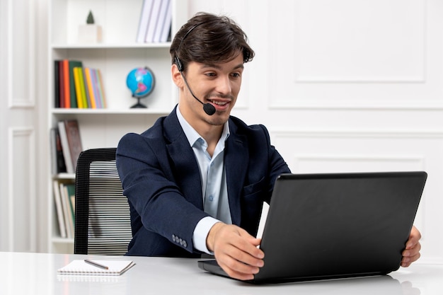 Customer service handsome guy with headset and laptop in suit happy looking at screen