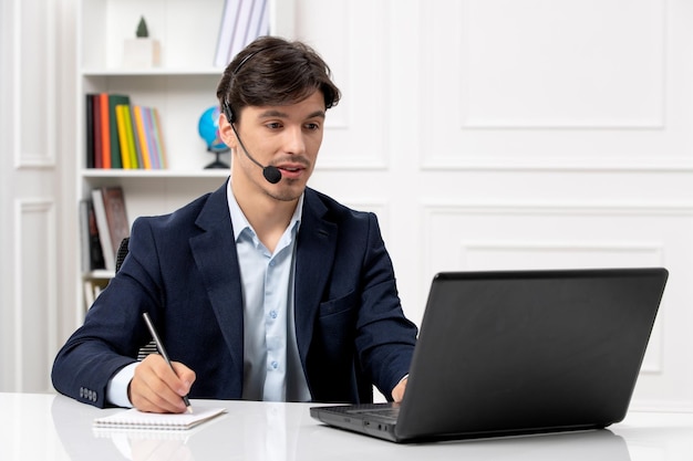 Customer service handsome guy with headset and laptop in suit taking down notes