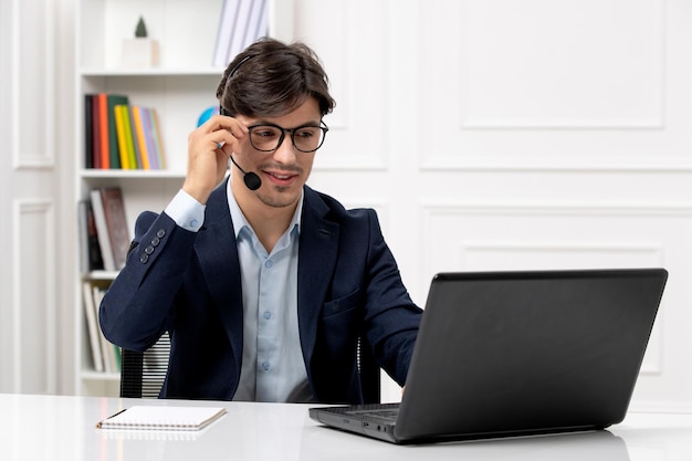 Customer service handsome guy with headset and laptop in suit touching edge of glasses