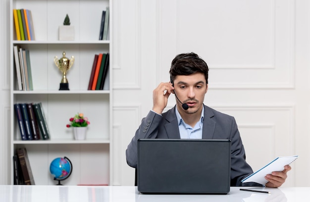 Customer service handsome man in grey suit with computer and headset having a conversation