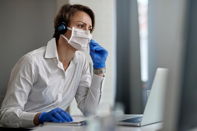 Foto gratuita rappresentante del servizio clienti che indossa una maschera protettiva mentre lavora al call center durante l'epidemia di virus