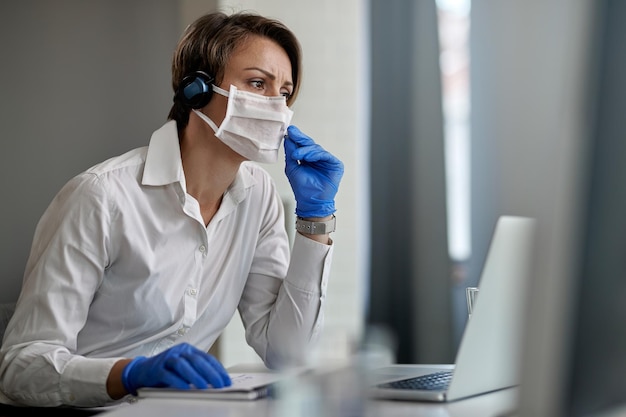Представитель службы поддержки клиентов в защитной маске во время работы в колл-центре во время эпидемии вируса