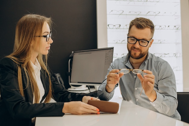 Free photo customer shoosing spectacles at optic store with the help of sales person