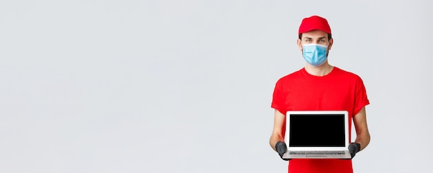 고객 지원 covid19 배달 패키지 온라인 주문 처리 개념 회사의 노트북 화면 웹 페이지를 보여주는 빨간색 유니폼 얼굴 마스크와 장갑을 입은 웃는 택배