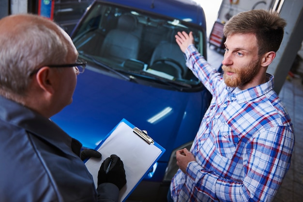 Foto gratuita cliente che parla con un meccanico in officina