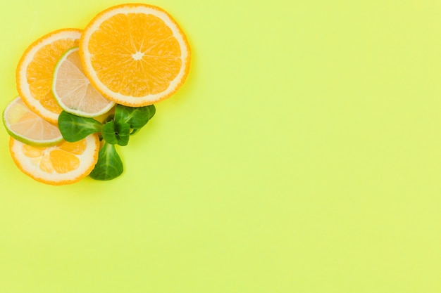 Cut ​​citrus fruits and green leaves on light background