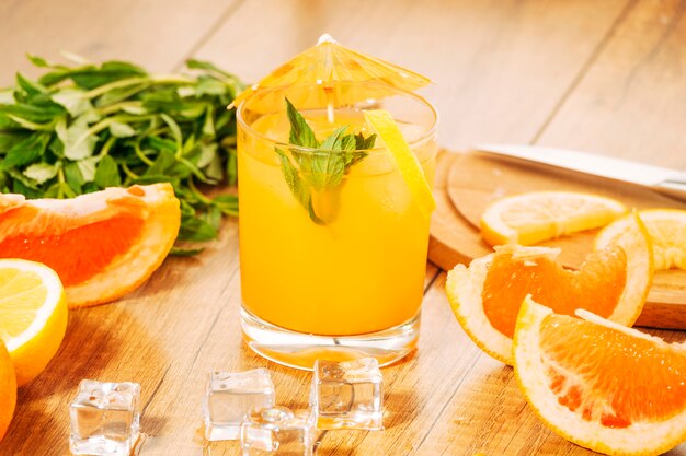 Разрезанные апельсиновые фрукты и сок с зонтиком