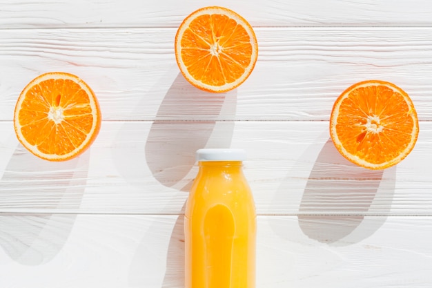 Free photo cut oranges with bottle of juice