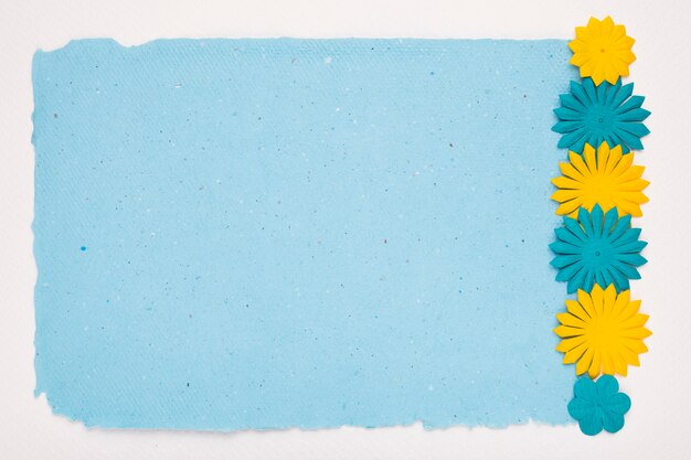 Cut out flowers border on blue paper over white backdrop