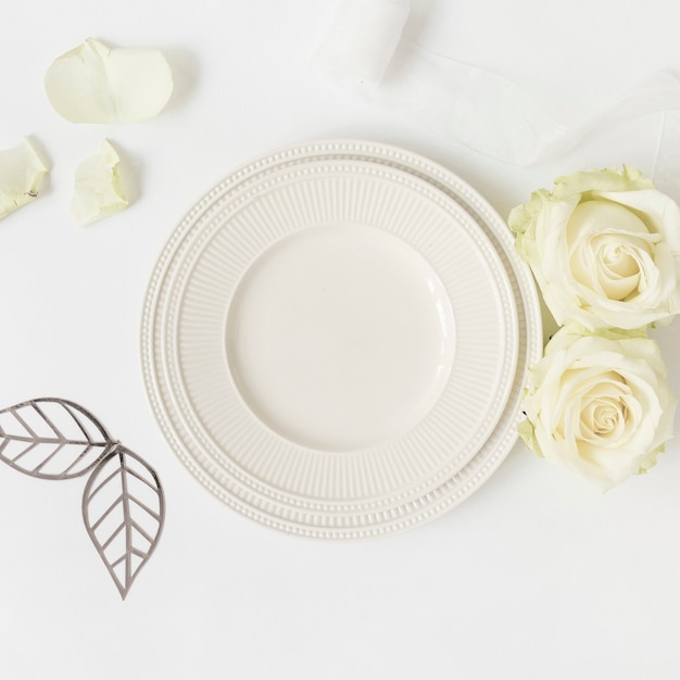 Cut out leaves; roses and ceramic plate; ribbon on white background