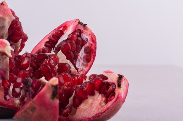 Cut ripe pomegranates on white wall.