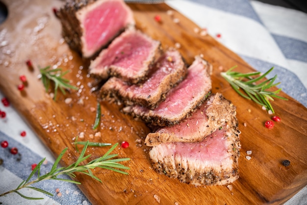 Free photo cut roasted beef sirloin with rosemary and pepper