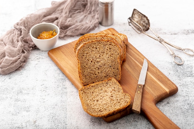 Cut slices of bread on wooden board with knife high view