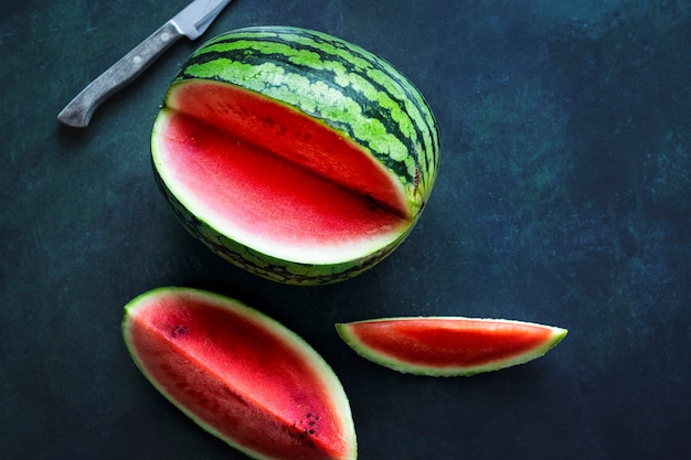 Cut watermelon and knife on blue table