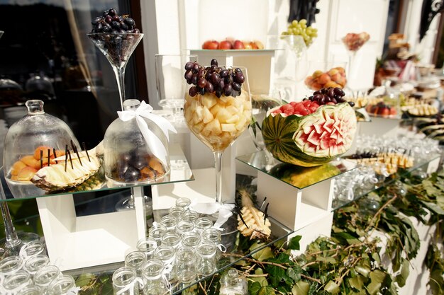 Cut watermelon stands on glass cube on table with fruits 