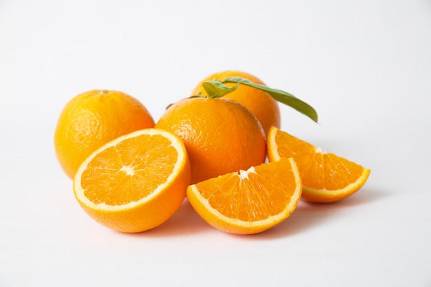 Нарезанные и целые оранжевые фрукты с зелеными листьями
