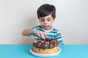 Cute adorable boy in studio eating chocolate cake