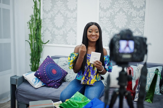 Cute african american woman making a video for her blog using a tripod mounted digital camera Young female blogger or vlogger on camera