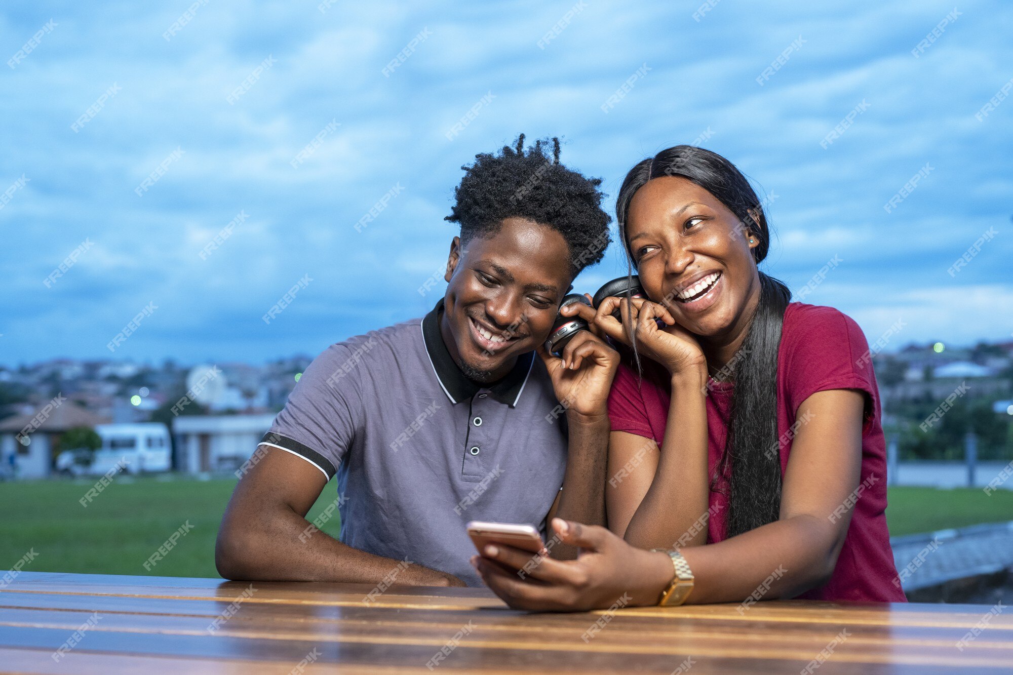 Free Photo | Cute african couple sitting in a park and watching a funny video together Free Photo | Cute african couple sitting in a park and watching a funny video together